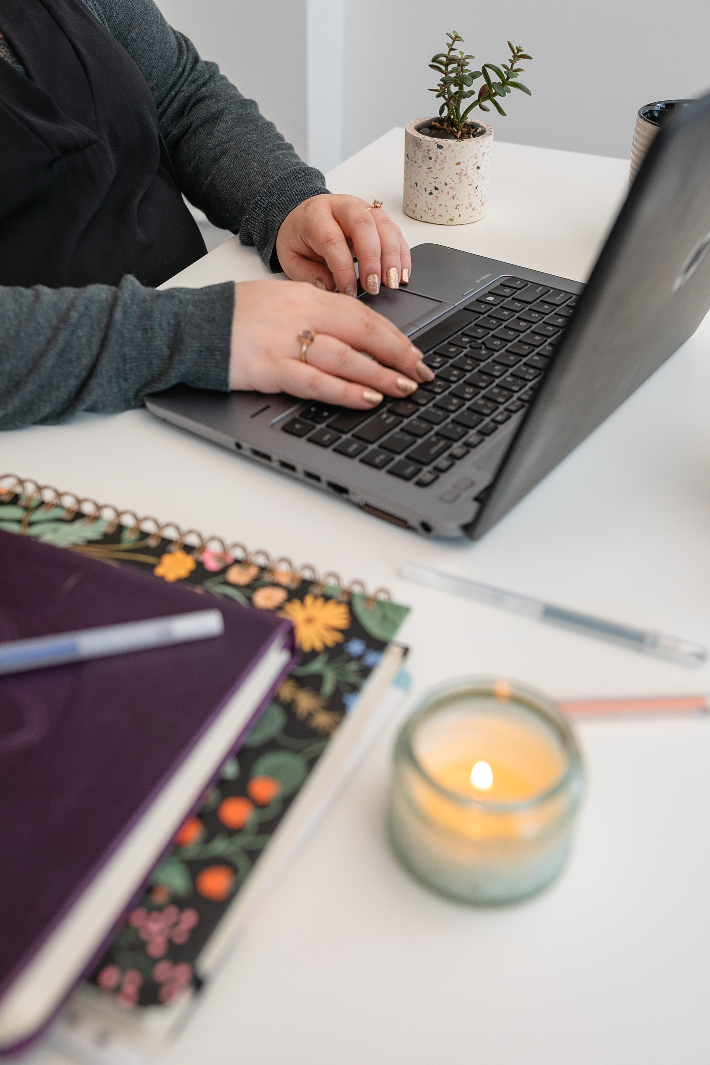 Career Coach, Jessica Wright, is shown (hands only) at laptop typing with journals, pen, and lit candle to the right of her.