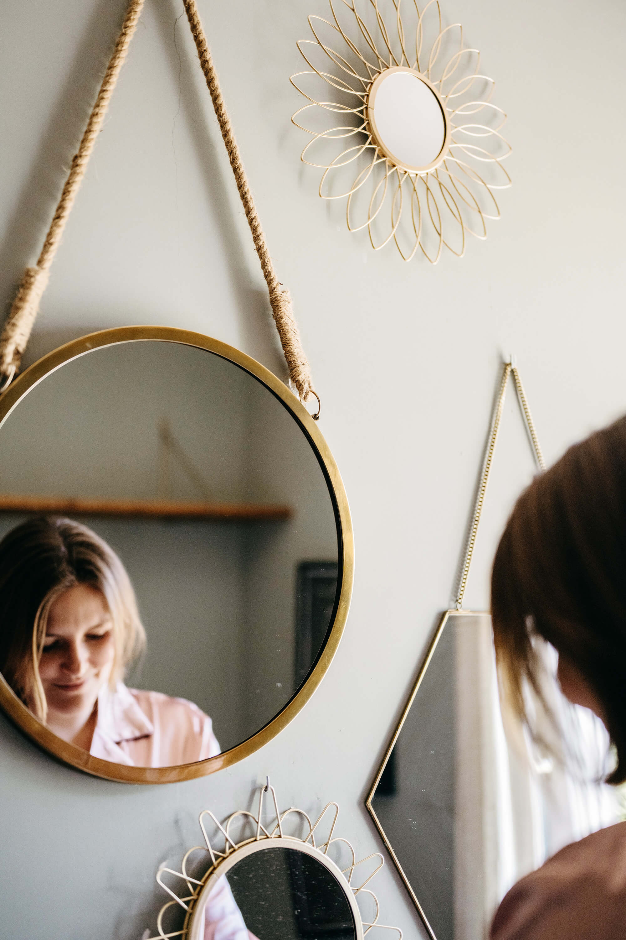 Woman looking into a mirror that is hanging on the wall.